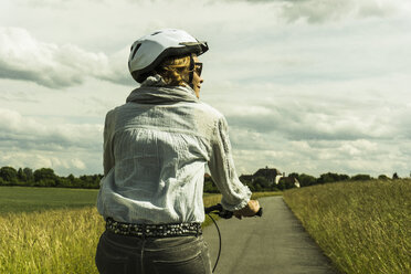 Frau fährt Fahrrad auf dem Lande - UUF004573