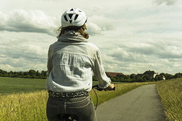 Frau fährt Fahrrad auf dem Lande - UUF004574