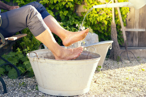 Man taking footbath in a garden - MAEF010642