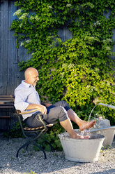 Lachender Mann beim Fußbad im Garten - MAEF010643