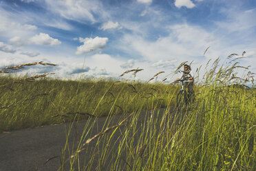 Frau fährt Fahrrad in der Natur - UUF004578