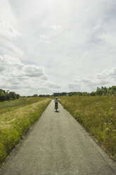 Frau fährt Fahrrad auf dem Lande - UUF004580