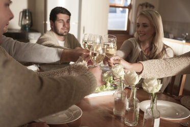 Friends clinking wine glasses at dinner table - ZEF006292