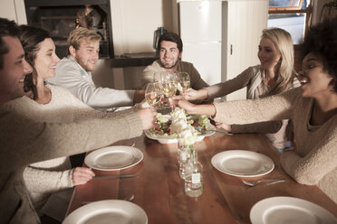 Friends clinking wine glasses at dinner table - ZEF006293