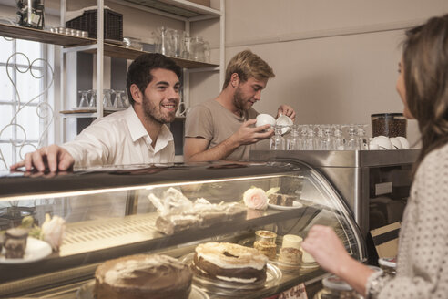 Young woman choosing cake from cake counter in coffee shop - ZEF006188