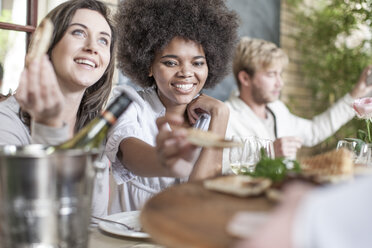 Freunde beim gemeinsamen Mittagessen im Restaurant, draußen sitzend - ZEF006210