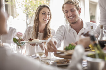 Freunde beim gemeinsamen Mittagessen im Restaurant, draußen sitzend - ZEF006211