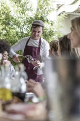 Waiter serving wine for friends lunching at restaurant - ZEF006212