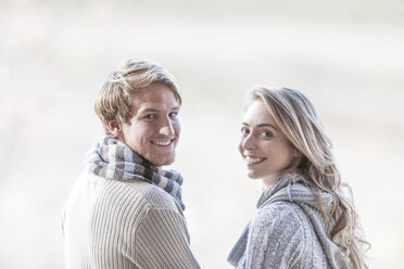 Portrait of smiling young couple looking over their shoulders - ZEF005773