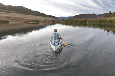 Back view of young man paddling on a lake - ZEF005786