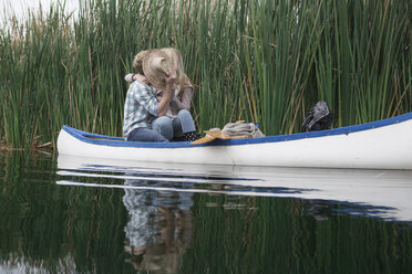 Junges Paar küsst sich in einem Kanu auf einem See und versteckt sich hinter einem Strohhut - ZEF005797