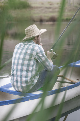 Fischer, der in einem Kanu auf einem See sitzt, lizenzfreies Stockfoto