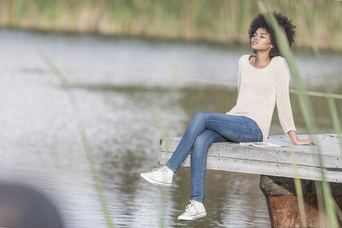 Frau entspannt sich auf einem Steg am See - ZEF005805
