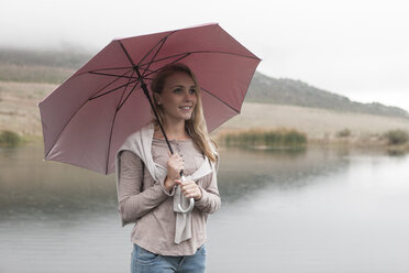 Junge Frau im Regen stehend mit Regenschirm - ZEF006224