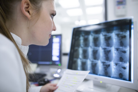 Junger Arzt im Krankenhaus schaut auf den Computerbildschirm, lizenzfreies Stockfoto