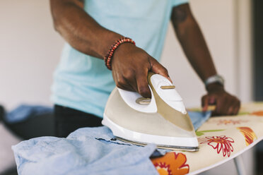 Young man ironing shirt at home - EBSF000660