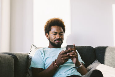 Young man at home reading messages on smart phone - EBSF000683