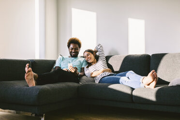 Young couple lying on couch looking at smart phone - EBSF000685