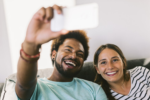 Glückliches junges Paar, das sich mit einem Smartphone fotografiert, lizenzfreies Stockfoto