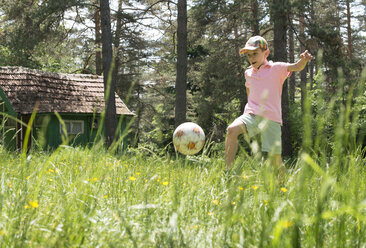 Junge spielt mit Fußball auf einer Wiese - DEGF000440