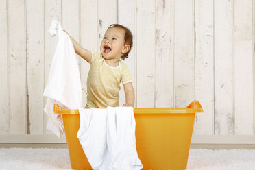 Kleines Mädchen in einem Wäschekorb stehend - DRF001652
