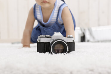 Die Kamera liegt auf dem Teppich, während das kleine Mädchen im Hintergrund krabbelt - DRF001659