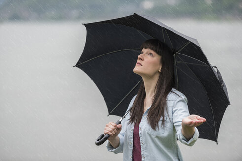 Young woman holding umbrella in rain - PAF001416