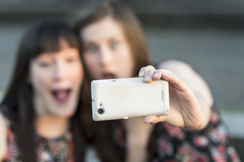 Zwei glückliche junge Frauen machen ein Selfie, lizenzfreies Stockfoto