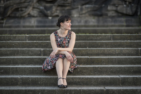 Deutschland, Koblenz, Deutsches Eck, junge Frau sitzt auf einer Treppe, lizenzfreies Stockfoto