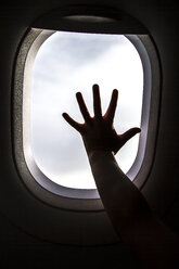 Silhouette of girl's hand on window on board of an airplane - JFEF000675