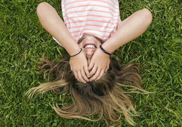 Girl lying on a meadow covering eyes with her hands - MGOF000278