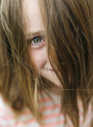 Porträt eines lächelnden Mädchens, das durch ihr Haar blickt - MGOF000275