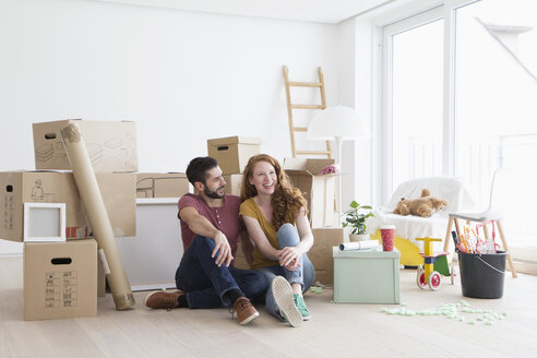 Junges Paar in neuer Wohnung mit Pappkartons, auf dem Boden sitzend - RBF002867