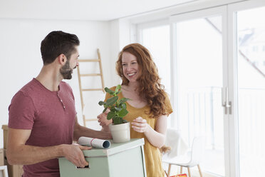 Junges Paar in neuer Wohnung mit Kartons beim Auspacken von Kisten - RBF002784