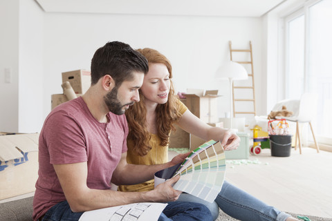 Junges Paar zieht in eine neue Wohnung ein und wählt Wandfarben aus, lizenzfreies Stockfoto