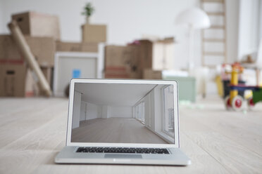 Laptop with picture of empty room in front of piled cardboard boxes - RBF002787