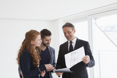 Junges Paar besichtigt Wohnung mit Immobilienmakler, lizenzfreies Stockfoto