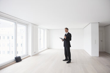 Estate agent standing in empty apartement - RBF002800