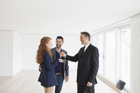 Estate agent handing over keys to young couple - RBF002806