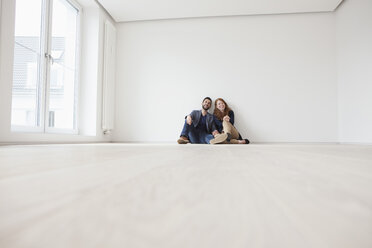 Young couple sitting on floor of their new flat - RBF002811