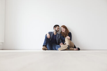Junges Paar sitzt auf dem Boden ihrer neuen Wohnung - RBF002812