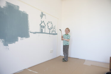 Kleiner Junge malt Haus und Baum an die Wand seines neuen Zimmers - RBF002827