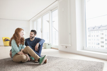 Young couple sitting on the floor of living room - RBF002835