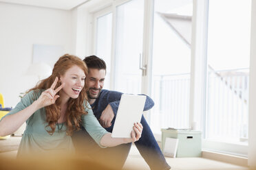 Lächelndes junges Paar macht ein Selfie mit digitalem Tablet im Wohnzimmer - RBF002837