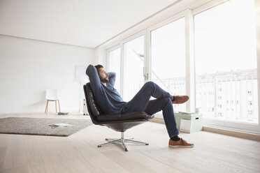 Young man relaxing on leather chair in his living room - RBF002845