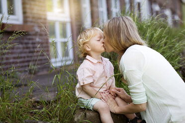 Mother kissing her little son in front of the house - GDF000752