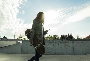 Junge Frau mit Skateboard und Smartphone - UUF004584