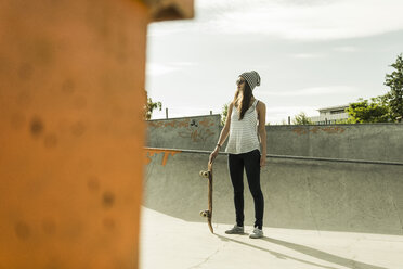 Junger Skateboarder mit Sonnenbrille und Kappe in einem Skatepark - UUF004595