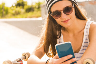 Junger Skateboarder mit Sonnenbrille und Smartphone - UUF004601