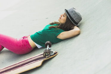 Junge Frau liegt neben ihrem Skateboard und ruht sich aus - UUF004609